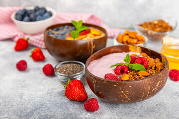 Bowl of granola with yogurt and fresh berries on a texture table. Yogurt berries, acai bowl, spirulina bowl. Healthy food, balanced breakfast. Strawberries, blueberries, kiwi, peach, almonds and chia.