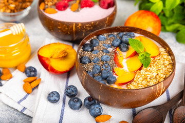 Bowl of granola with yogurt and fresh berries on a texture table. Yogurt berries, acai bowl, spirulina bowl. Healthy food, balanced breakfast. Strawberries, blueberries, kiwi, peach, almonds and chia.