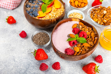Bowl of granola with yogurt and fresh berries on a texture table. Yogurt berries, acai bowl, spirulina bowl. Healthy food, balanced breakfast. Strawberries, blueberries, kiwi, peach, almonds and chia.