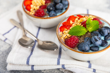 Bowl of granola with yogurt and fresh berries on a texture table. Yogurt berries, acai bowl, spirulina bowl. Healthy food, balanced breakfast. Strawberries, blueberries, kiwi, peach, almonds and chia.