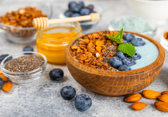 Bowl of granola with yogurt and fresh berries on a texture table. Yogurt berries, acai bowl, spirulina bowl. Healthy food, balanced breakfast. Strawberries, blueberries, kiwi, peach, almonds and chia.