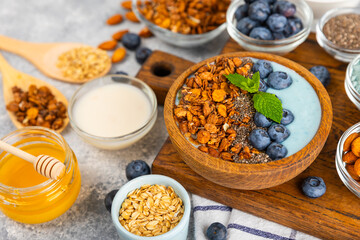 Bowl of granola with yogurt and fresh berries on a texture table. Yogurt berries, acai bowl, spirulina bowl. Healthy food, balanced breakfast. Strawberries, blueberries, kiwi, peach, almonds and chia.