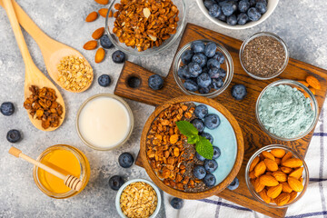 Bowl of granola with yogurt and fresh berries on a texture table. Yogurt berries, acai bowl, spirulina bowl. Healthy food, balanced breakfast. Strawberries, blueberries, kiwi, peach, almonds and chia.