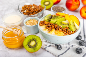 Bowl of granola with yogurt and fresh berries on a texture table. Yogurt berries, acai bowl, spirulina bowl. Healthy food, balanced breakfast. Strawberries, blueberries, kiwi, peach, almonds and chia.