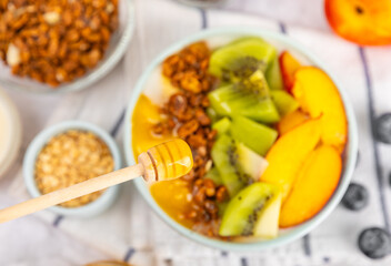 Bowl of granola with yogurt and fresh berries on a texture table. Yogurt berries, acai bowl, spirulina bowl. Healthy food, balanced breakfast. Strawberries, blueberries, kiwi, peach, almonds and chia.