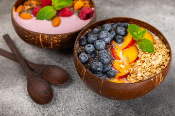 Bowl of granola with yogurt and fresh berries on a texture table. Yogurt berries, acai bowl, spirulina bowl. Healthy food, balanced breakfast. Strawberries, blueberries, kiwi, peach, almonds and chia.