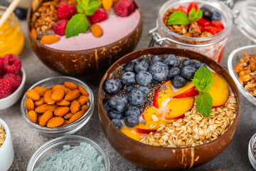 Bowl of granola with yogurt and fresh berries on a texture table. Yogurt berries, acai bowl, spirulina bowl. Healthy food, balanced breakfast. Strawberries, blueberries, kiwi, peach, almonds and chia.