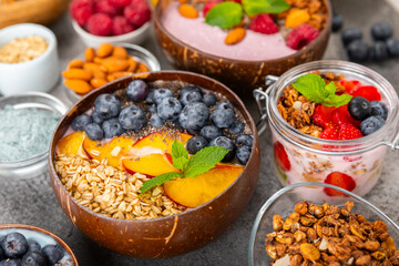 Bowl of granola with yogurt and fresh berries on a texture table. Yogurt berries, acai bowl, spirulina bowl. Healthy food, balanced breakfast. Strawberries, blueberries, kiwi, peach, almonds and chia.