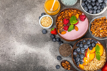 Bowl of granola with yogurt and fresh berries on a texture table. Yogurt berries, acai bowl, spirulina bowl. Healthy food, balanced breakfast. Strawberries, blueberries, kiwi, peach, almonds and chia.