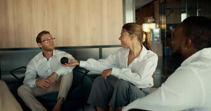 Group therapy for office workers. People in a company take turns expressing their opinion and passing a black ball to each other in the office