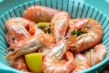 Cooked cooked king prawns with lemon in colander.