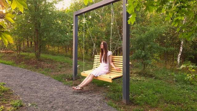 Cute woman swinging on swing in city park
