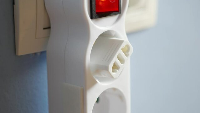 Connecting an electrical adapter to an electric splitter with red switch in a hotel room while traveling