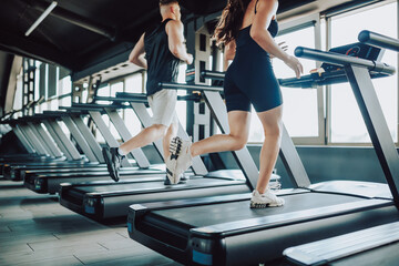 Fototapeta na wymiar Hispanic and American Couple run treadmill Fitness in the Gym. Caucasian Man and Hispanic Woman Engaged in Intense Workout. Young Fit Couple Training Together at the Gym