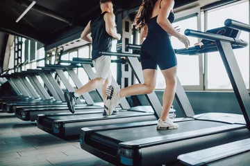 Papier Peint photo Fitness Hispanic and American Couple run treadmill Fitness in the Gym. Caucasian Man and Hispanic Woman Engaged in Intense Workout. Young Fit Couple Training Together at the Gym