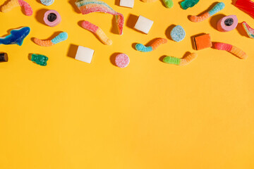 Assorted candies on bright yellow background