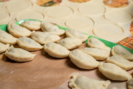 Homemade dumplings cobbled together by hand on paper. Sculpting dumplings in kitchen.
