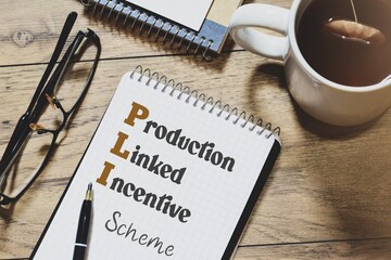 Notepad with the inscription Production Linked Incentive (PLI) scheme on desk. Business strategy to boost local production.