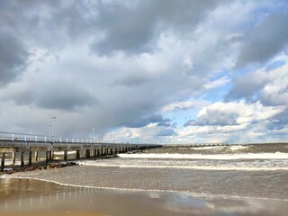 Winter beach with snow clouds and blue sky in day time water