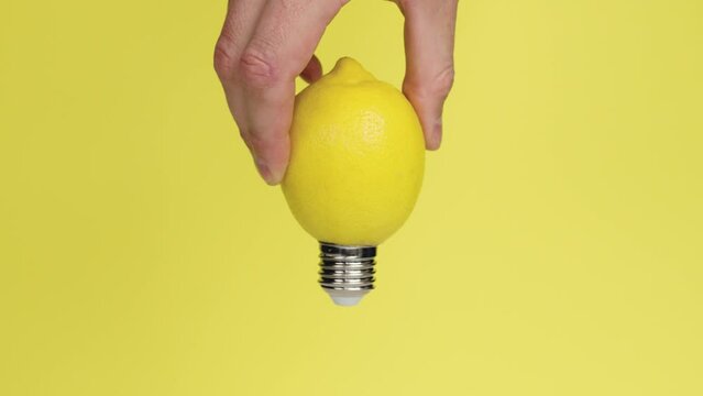 Yellow lemon light bulb in hand on a yellow background. Conceptual abstract idea. Creative invention concept