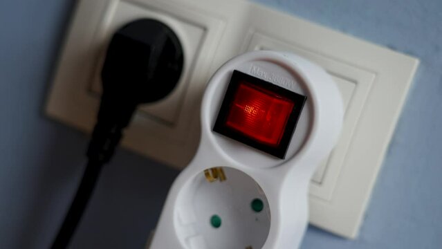 Turning on a glowing electrical splitter switch in a room close-up