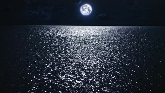 Beautiful and mystical night scene. The full moon hangs over the night surface of the river. The river reflects the light of the moon, and creates a glare.