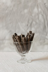 Appetizing chocolate waffles in a glass candy bowl plate on a table on a gray background. Creamy texture of waffle cookies. Waffle dessert.