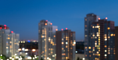 Fototapeta na wymiar Unfocused background: evening city lights of high-rise buildings. Evening city lights banner