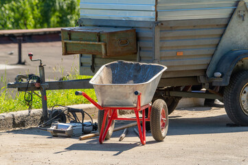 Empty construction wheelbarrow near car trailer