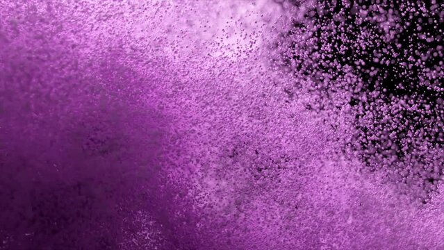Violet particles fly on a black background. The wind blows away colored sand. Powder. Spray. Texture. 3d animation