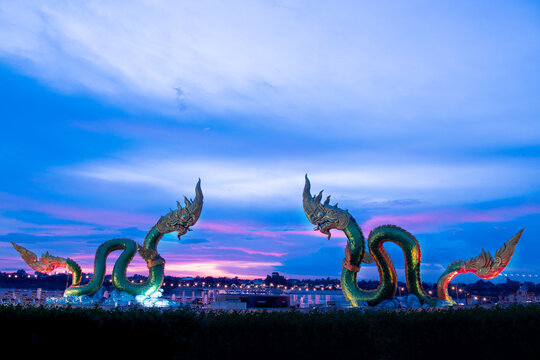 Big green naga statue in riverside on mekong river is landmark in nongkhai city Thailand with twilight background.