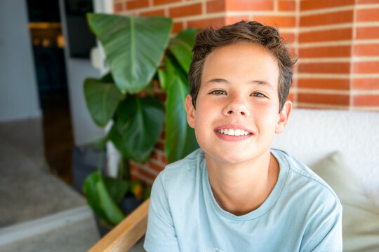 Close up portrait of a young hispanic teenager man looking at camera with a joyful smiling expression outdoors.