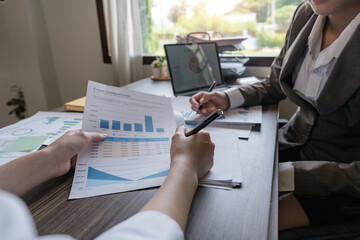 Two Asian business women Discussing Financial reports, analytical concepts, planning and financial statistics and investment markets at the office
