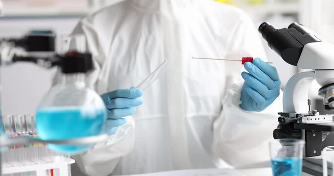 Scientist Chemist in anti-plague protective suit pulling out cotton swab from test tube in laboratory 4k movie. Scientific research on coronavirus infection concept
