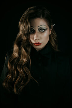 Portrait of a young woman in a Gothic gloomy image of a witch or vampire. Halloween costume. Vertical photo.