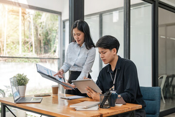 Two Asian businessmen met in the office and pointed to analysis charts and graphs of business growth and financial performance