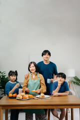 ￼￼￼Asian family making food in kitchen at home. Portrait of smiling mother, dad and children standing with dough bake cookie and cake ingredientat cooking counter