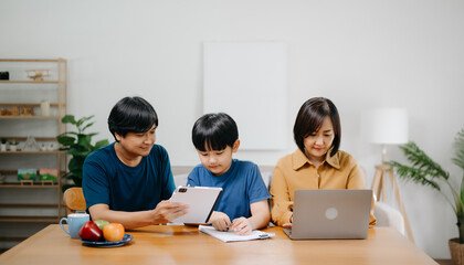 Parents assisting children doing homework on desk. asian son is doing a homework on the notebook at home