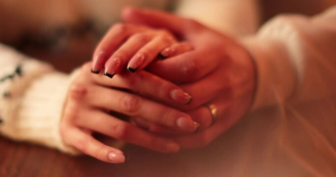 Close-up of the hands of a couple in love sitting at a table in a cafe on a romantic date. Male and female hands interacting with each other at the moment of a romantic meeting of a couple in love.