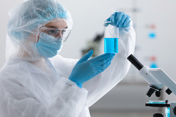 Young scientist holding beaker with sample in laboratory