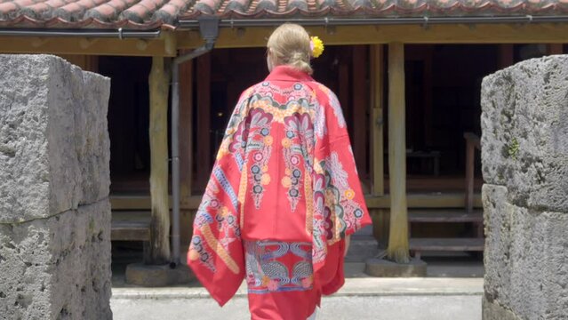 Woman getting traditional japanese house at Okinawa world Naha Japan wearing ryusou kimono dress summer hot day wooden stone house get off geta shoes