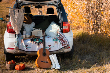 picnic in the trunk of a car with guitaron sunset outside. Domestic travel concept.