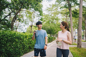 young Asian couple staying hydrated after running jogging. Healthy lifestyle concept.