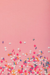 Colorful star shaped sugar sprinkles on pink background