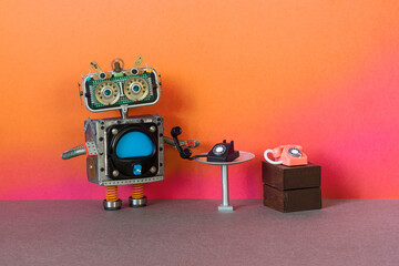 Toy robot bot holds a handset of an old vintage rotary phone in his hand. The concept of analog...