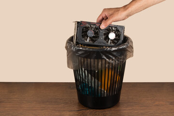 throwing a video card in the trash bin, a computer video card in hand in front of the trash bin
