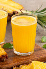 Fresh delicious pineapple juice smoothie in glass cup on gray table background.