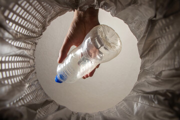 recycling, waste sorting and sustainability concept - hand throwing plastic bottle into trash can...