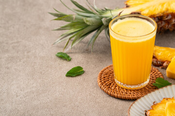 Fresh delicious pineapple juice smoothie in glass cup on gray table background.