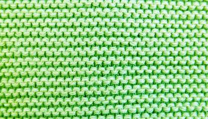 Close up background of knitted green wool fabric knitwear texture. 